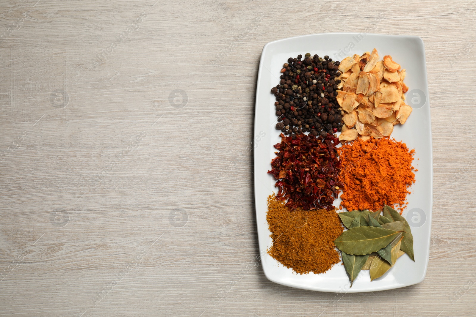 Photo of Plate with different spices on light table, top view. Space for text