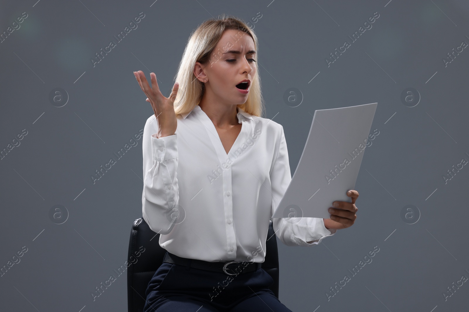 Photo of Casting call. Emotional woman with script performing against grey background