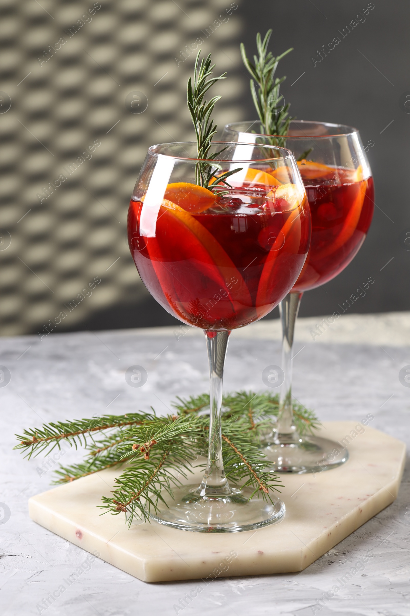 Photo of Christmas Sangria cocktail in glasses and fir tree branch on grey textured table