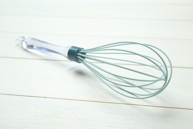 One whisk on white wooden table, closeup