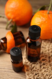 Bottles of tangerine essential oil, fresh fruit and peel on wooden table