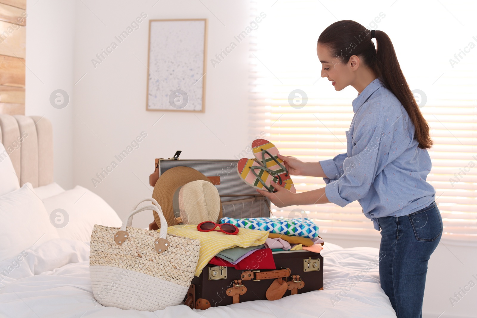 Photo of Woman packing suitcase for summer vacation in bedroom