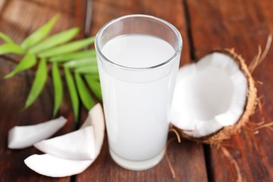 Photo of Glass of coconut water, leaf and nuts on wooden table