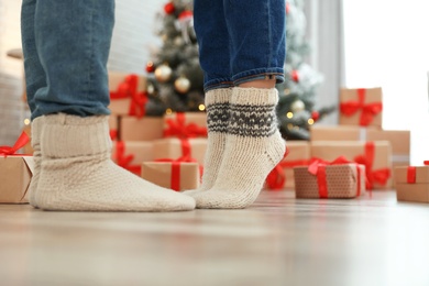 Image of Couple in warm socks in room decorated for Christmas, closeup