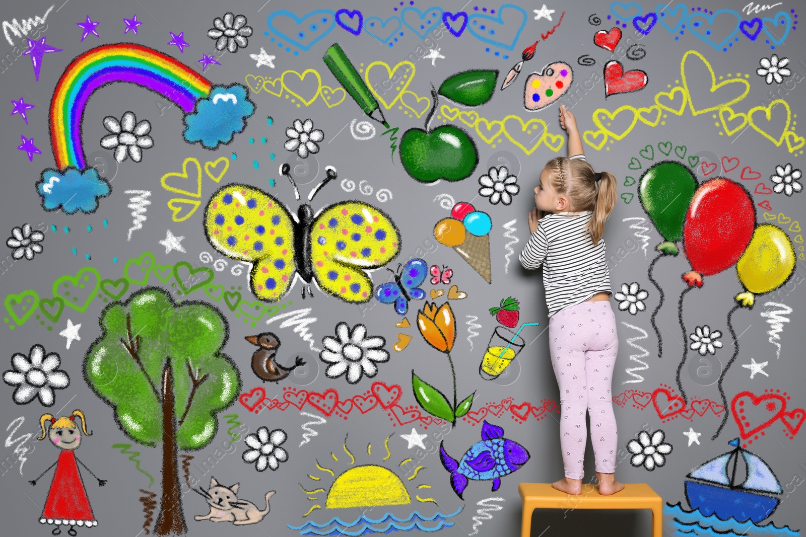 Image of Little child drawing with colorful chalk on gray wall