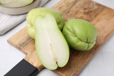 Cut and whole chayote on white tiled table, closeup