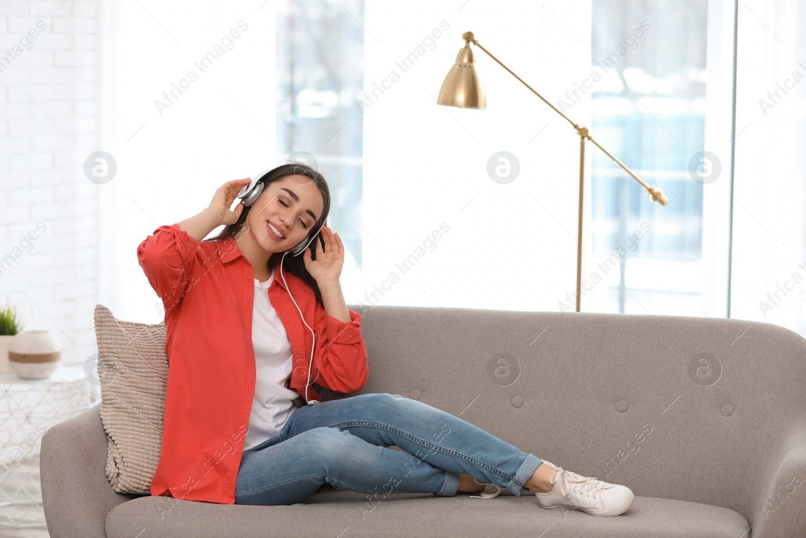 Photo of Young woman with headphones enjoying music in living room