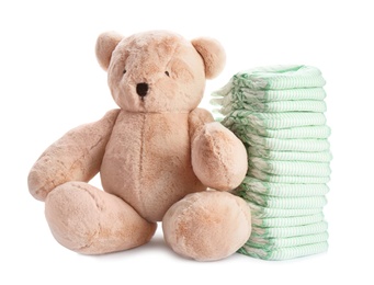 Photo of Stack of diapers and teddy bear on white background. Baby accessories