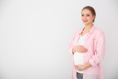 Young pregnant woman on white background. Space for text