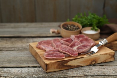 Photo of Board with slices of raw beef tongue and products on wooden table, closeup. Space for text