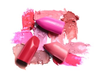 Different lipsticks and smears on white background, top view