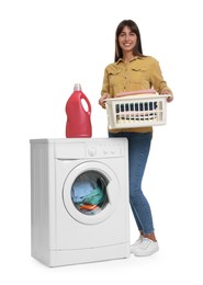 Photo of Beautiful woman with laundry basket and detergent near washing machine against white background