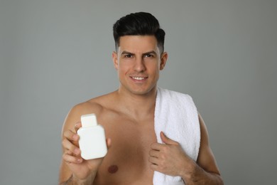 Photo of Handsome man holding post shave lotion on grey background