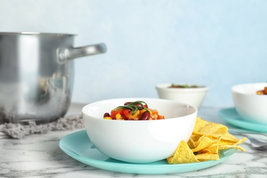 Photo of Bowl with tasty chili con carne served on marble table