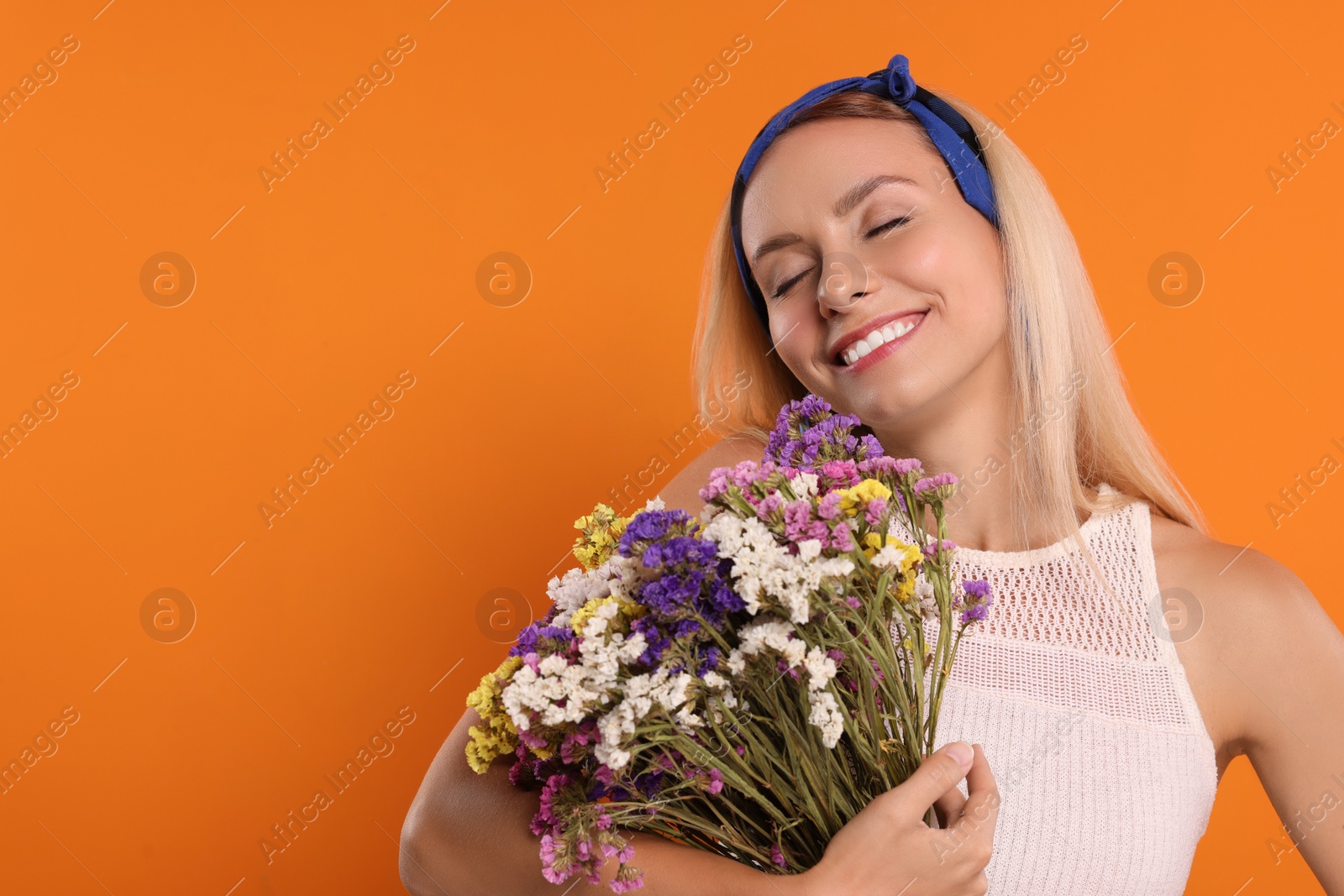 Photo of Happy hippie woman with bouquet of flowers on orange background. Space for text