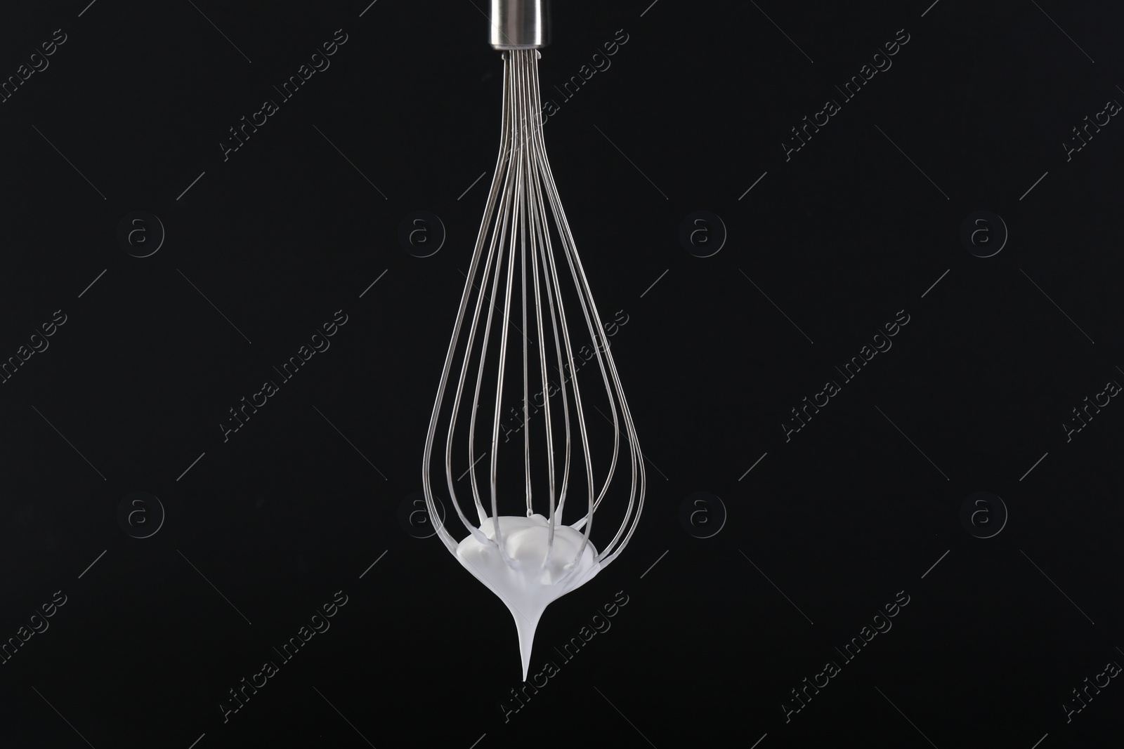 Photo of Whisk with whipped cream on black background