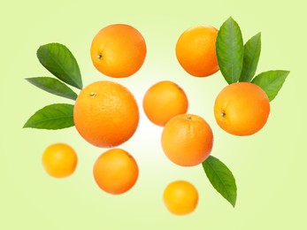 Image of Ripe oranges with leaves flying on pale green background