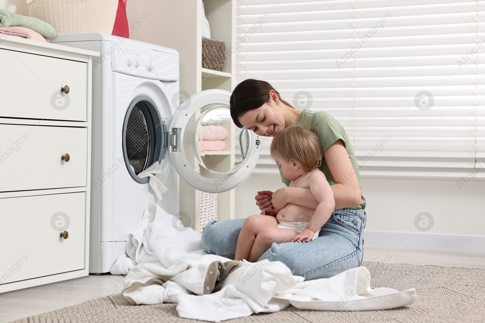 Photo of Happy mother with her daughter washing baby clothes in bathroom