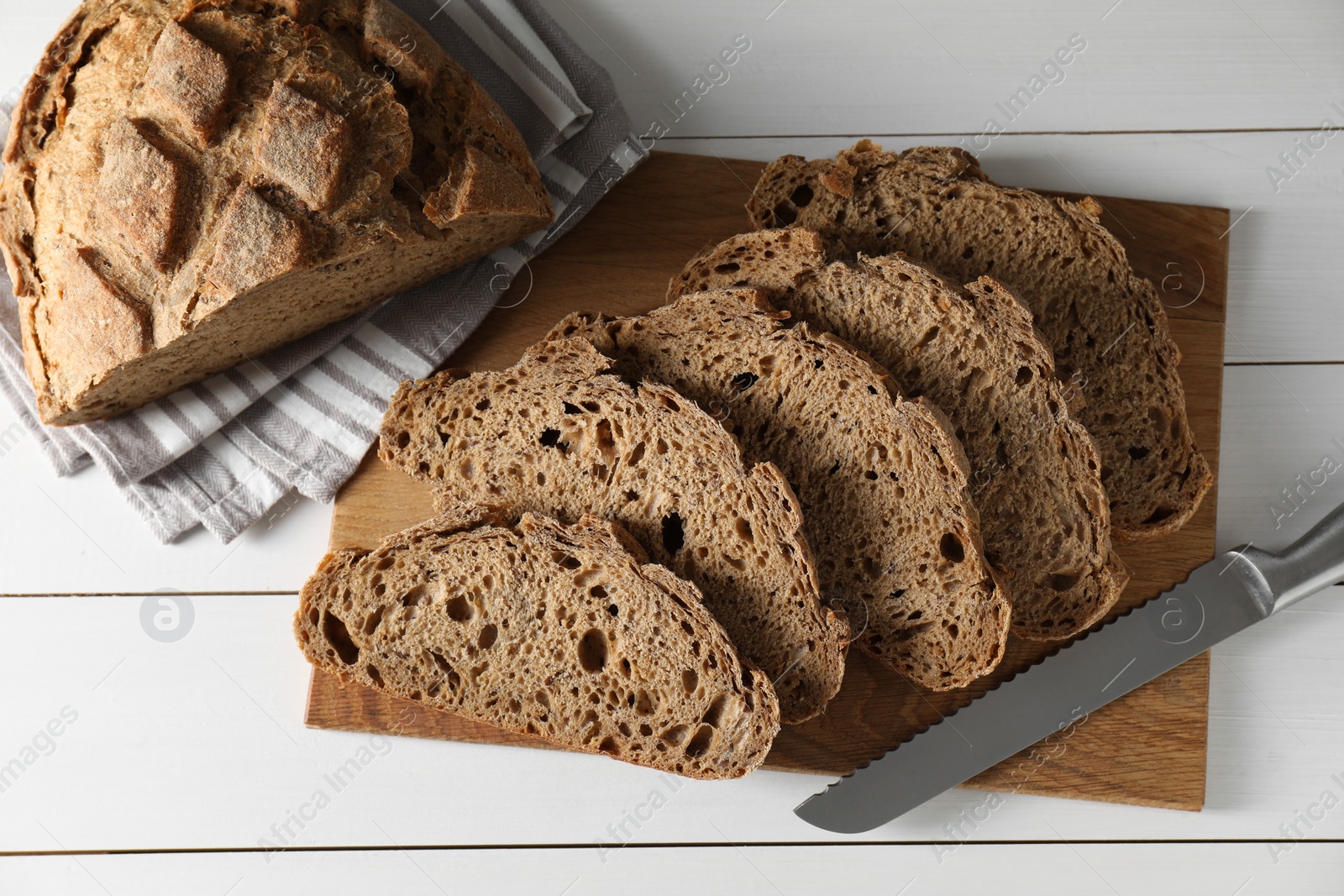 Photo of Freshly baked cut sourdough bread on white wooden table, top view