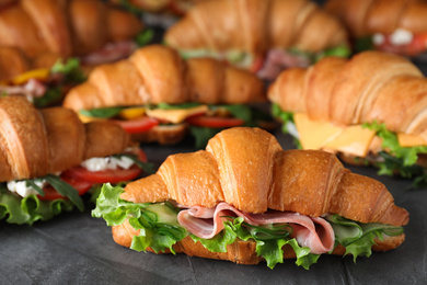 Photo of Bunch of tasty croissant sandwiches on grey table