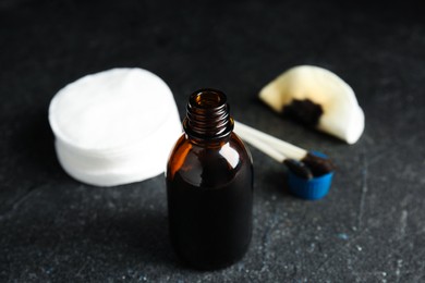 Photo of Bottle of medical iodine, cotton pads and buds on black table, closeup