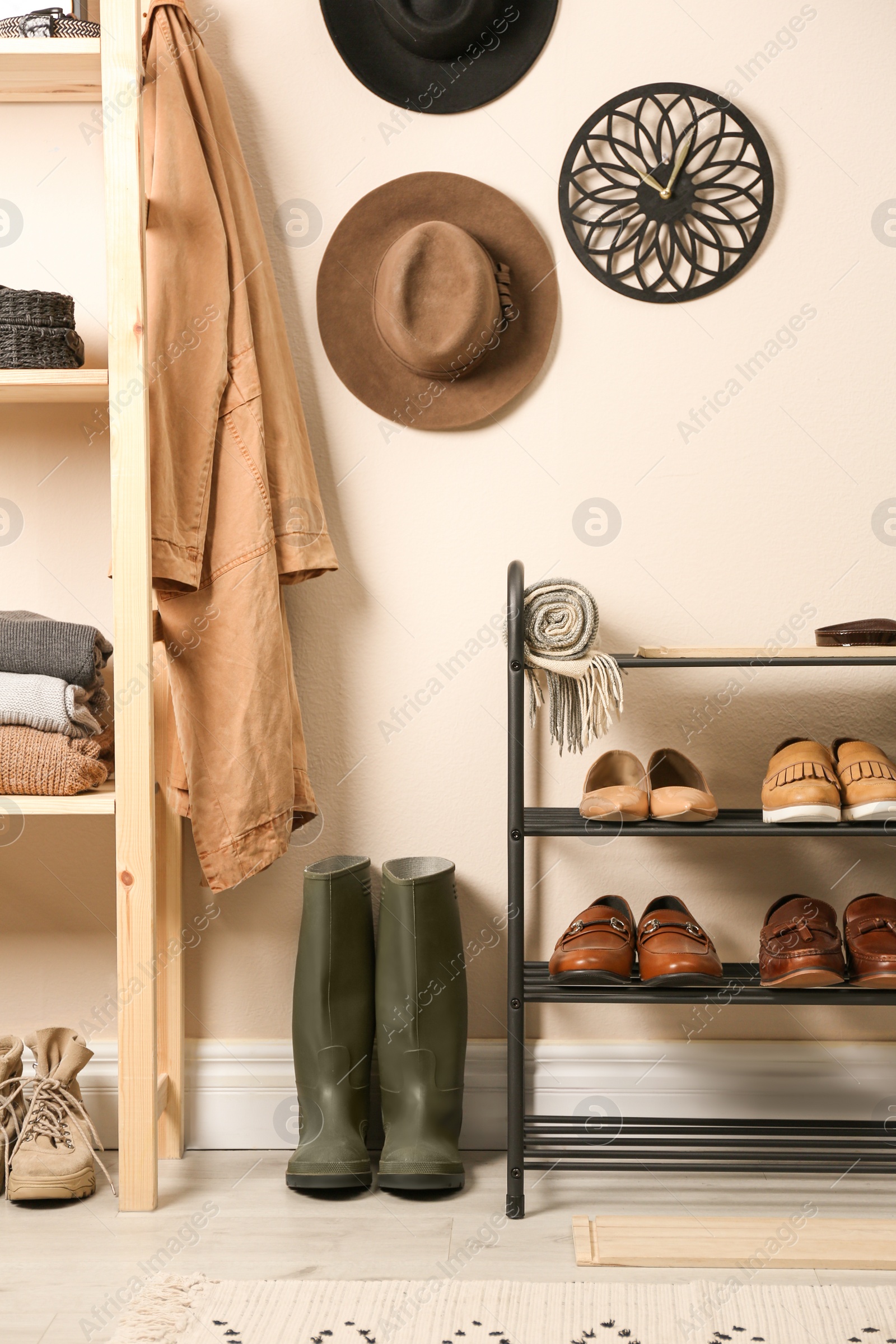 Photo of Rack with different shoes near beige wall in room