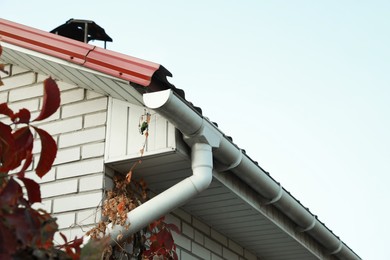 Photo of Rain gutter system with drainpipe on house outdoors