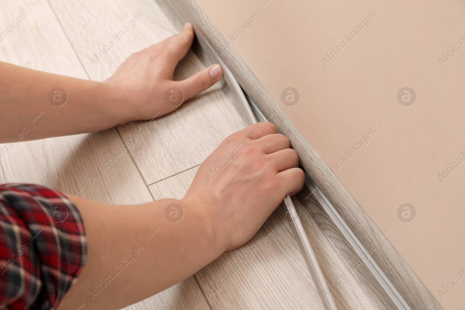 Photo of Man installing plinth on laminated floor in room, closeup