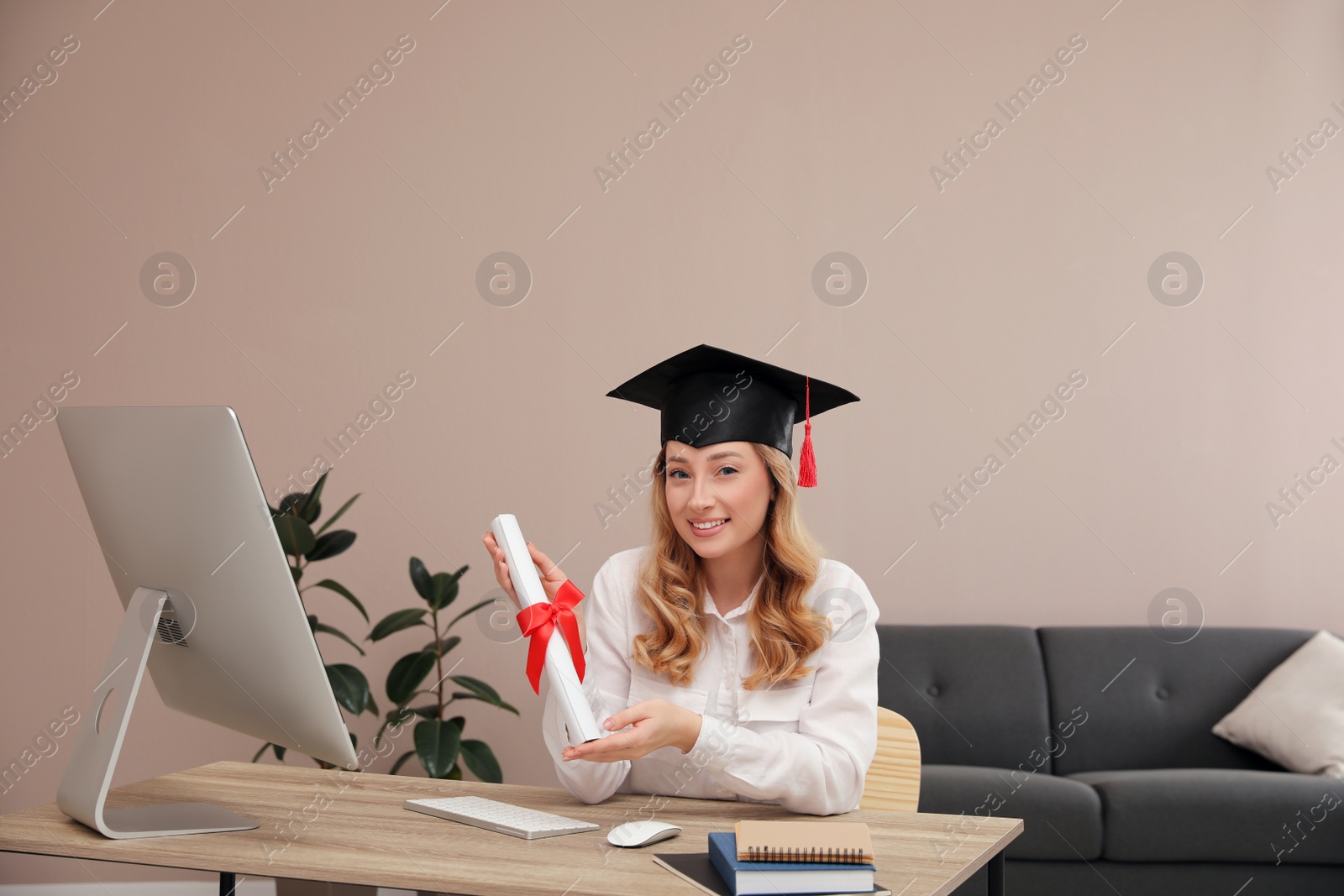 Photo of Happy student with graduation hat and diploma at workplace in office