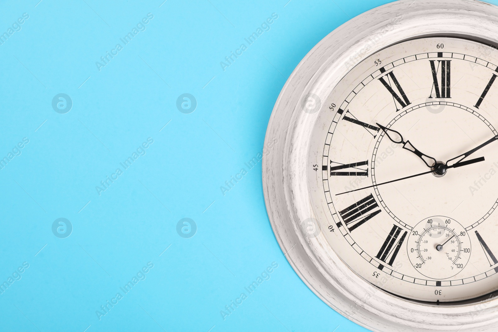 Photo of Stylish vintage wall clock on turquoise background, top view with space for text