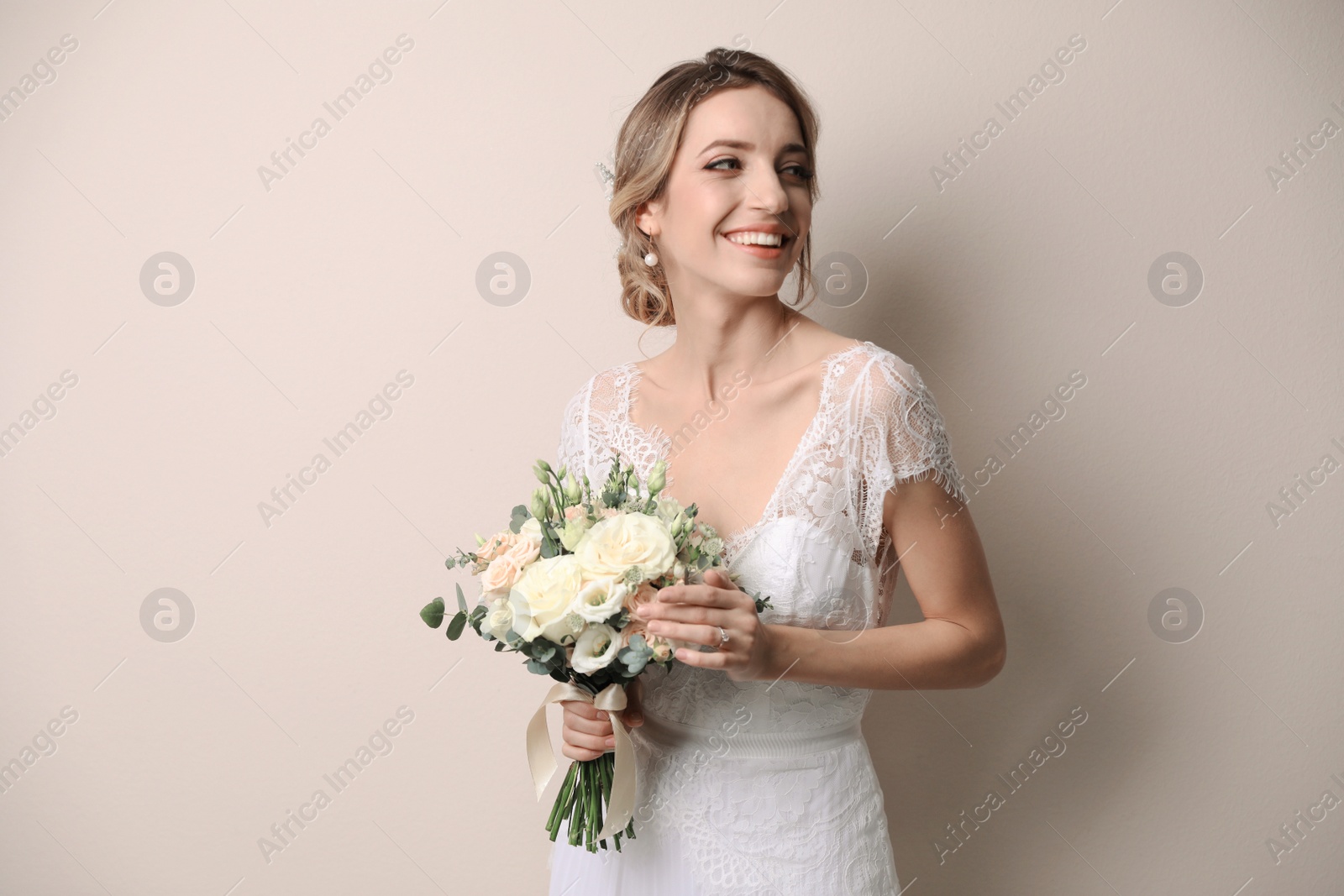 Photo of Young bride with beautiful wedding bouquet on beige background