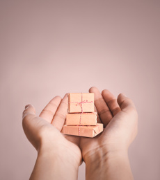 Image of Boxing day. Woman with gifts on beige background, closeup