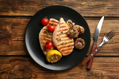 Photo of Tasty grilled chicken fillets served on wooden table, flat lay