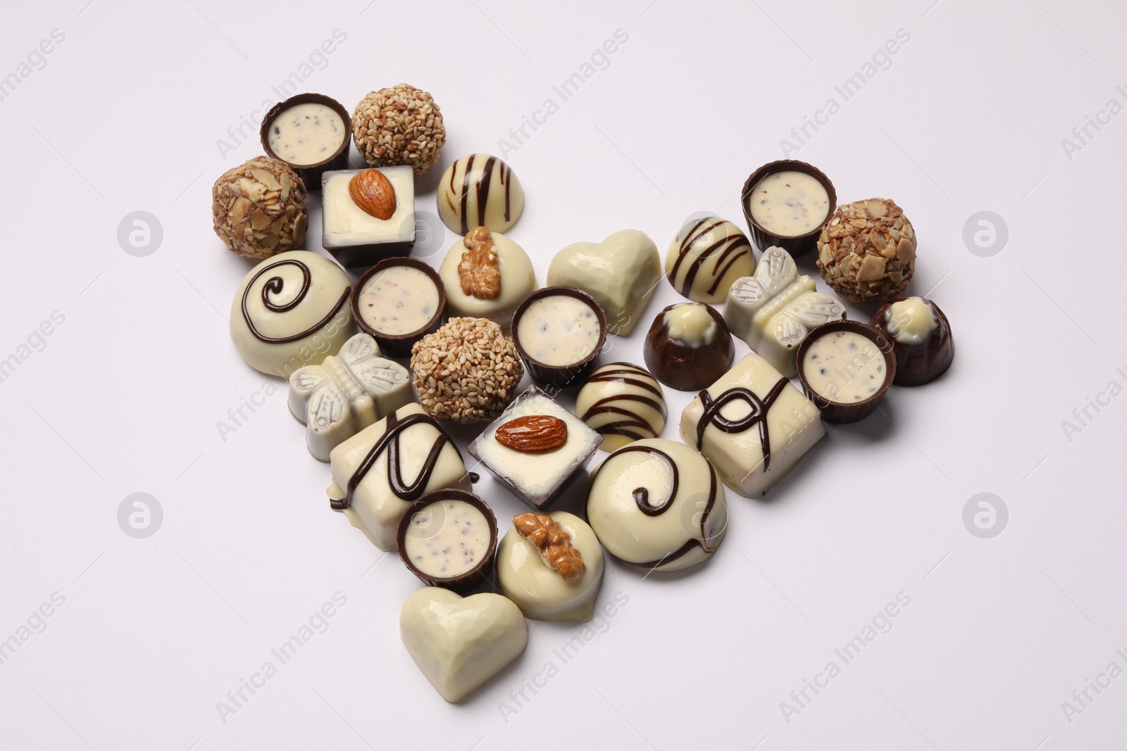 Photo of Heart made with delicious chocolate candies on white background, above view