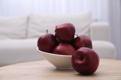 Photo of Red apples in bowl on wooden table indoors