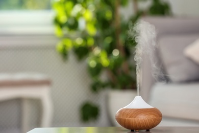 Aroma oil diffuser lamp on table against blurred background