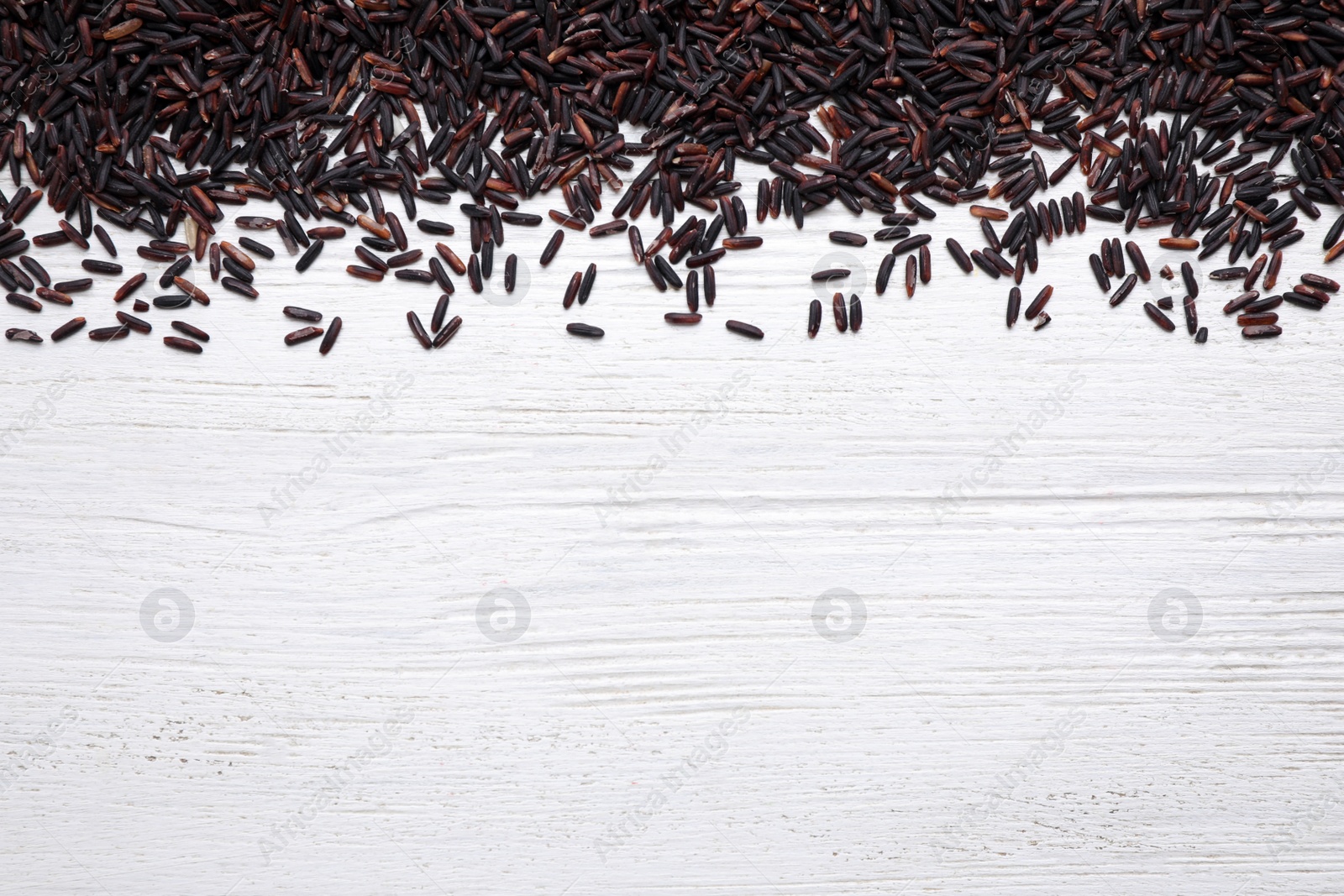 Photo of Brown rice on white wooden table, top view