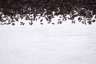 Photo of Brown rice on white wooden table, top view