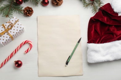 Flat lay composition with paper and Christmas decor on white wooden table. Writing letter to Santa Claus