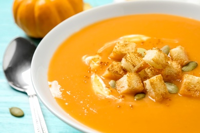Photo of Tasty creamy pumpkin soup with croutons and seeds in bowl on table, closeup