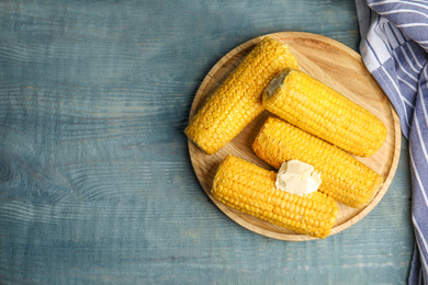 Photo of Delicious boiled corn with butter on light blue wooden table, flat lay. Space for text