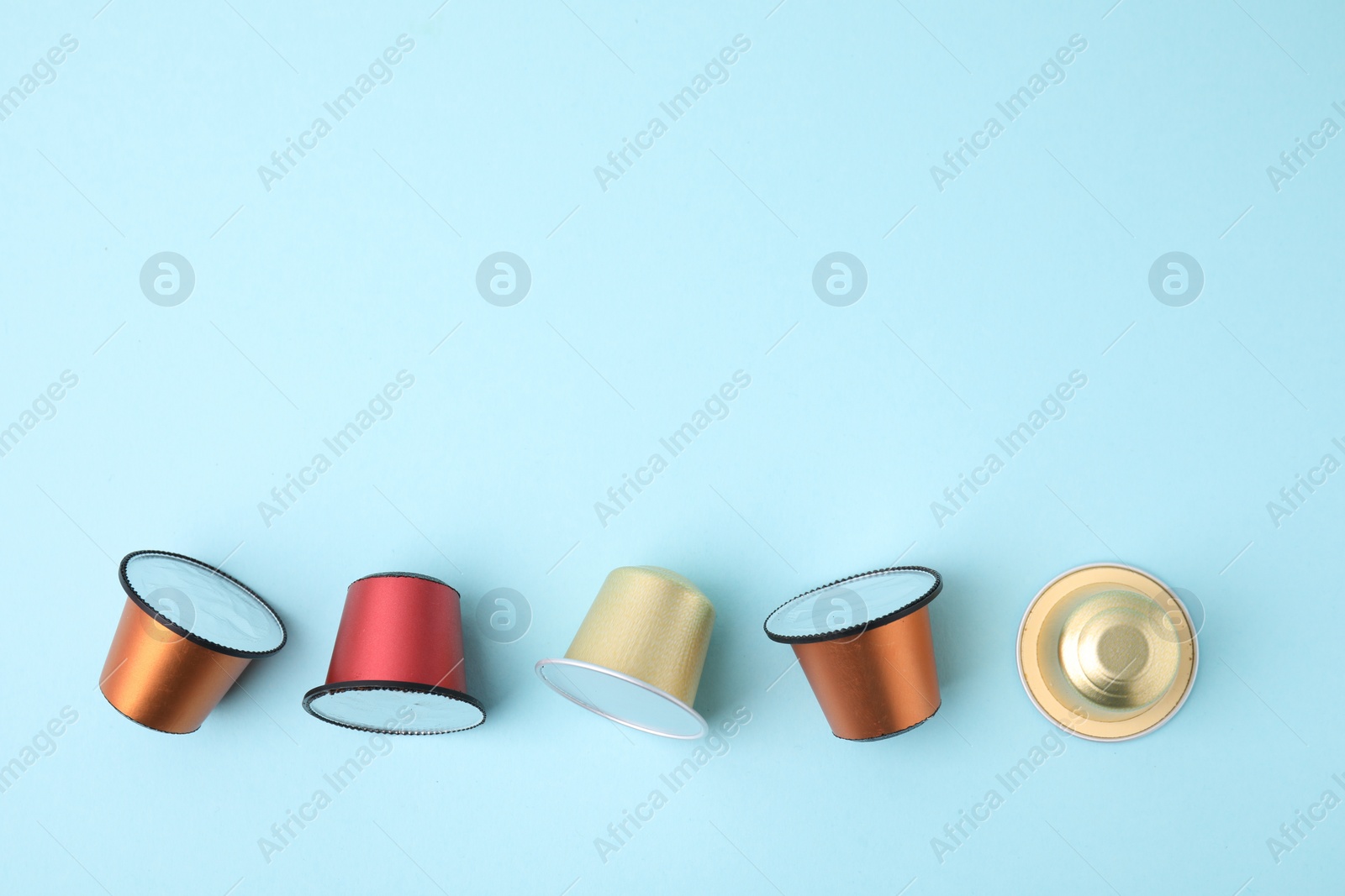 Photo of Many coffee capsules on light blue background, flat lay. Space for text