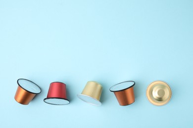 Photo of Many coffee capsules on light blue background, flat lay. Space for text