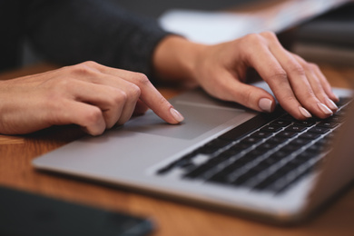 Photo of Woman working on modern laptop at table, closeup