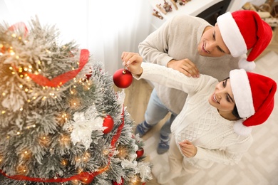 Photo of Happy couple decorating Christmas tree at home