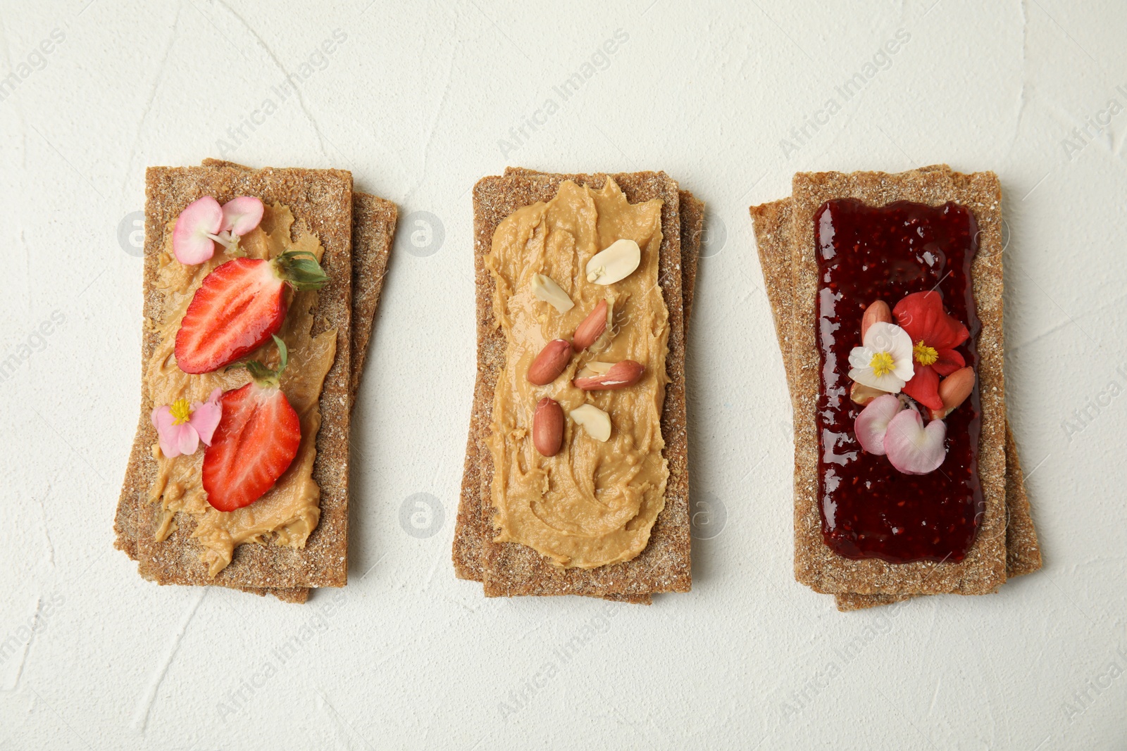 Photo of Fresh rye crispbreads with different toppings on white table, flat lay
