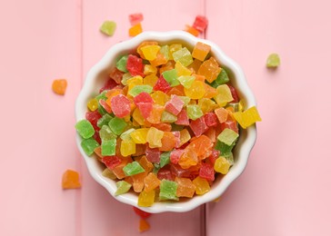 Photo of Mix of delicious candied fruits in bowl on pink wooden table, top view