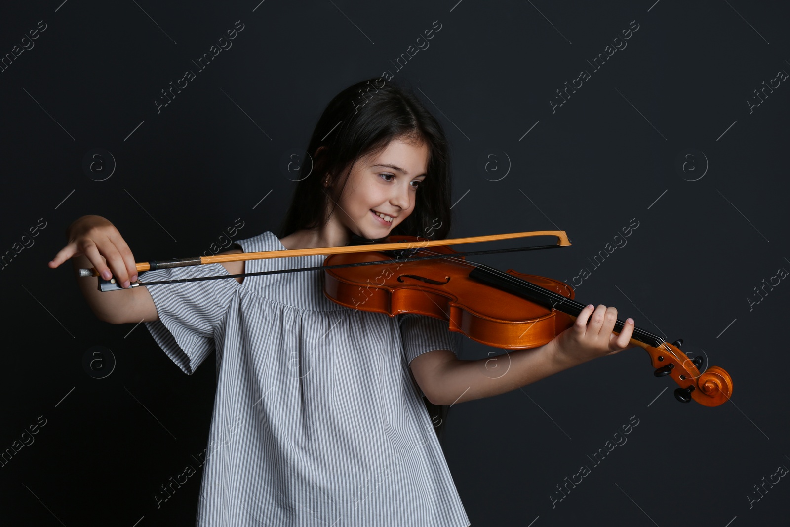 Photo of Preteen girl playing violin on black background