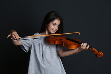 Photo of Preteen girl playing violin on black background