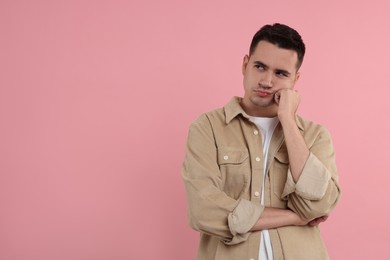 Resentful man on pink background, space for text